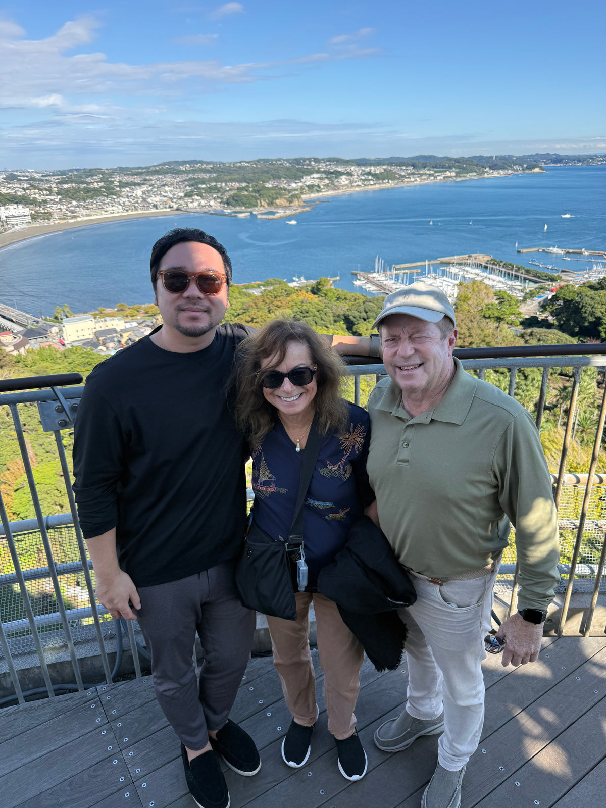 Roy Masuko with two clients on an observation deck above a coastal bay.