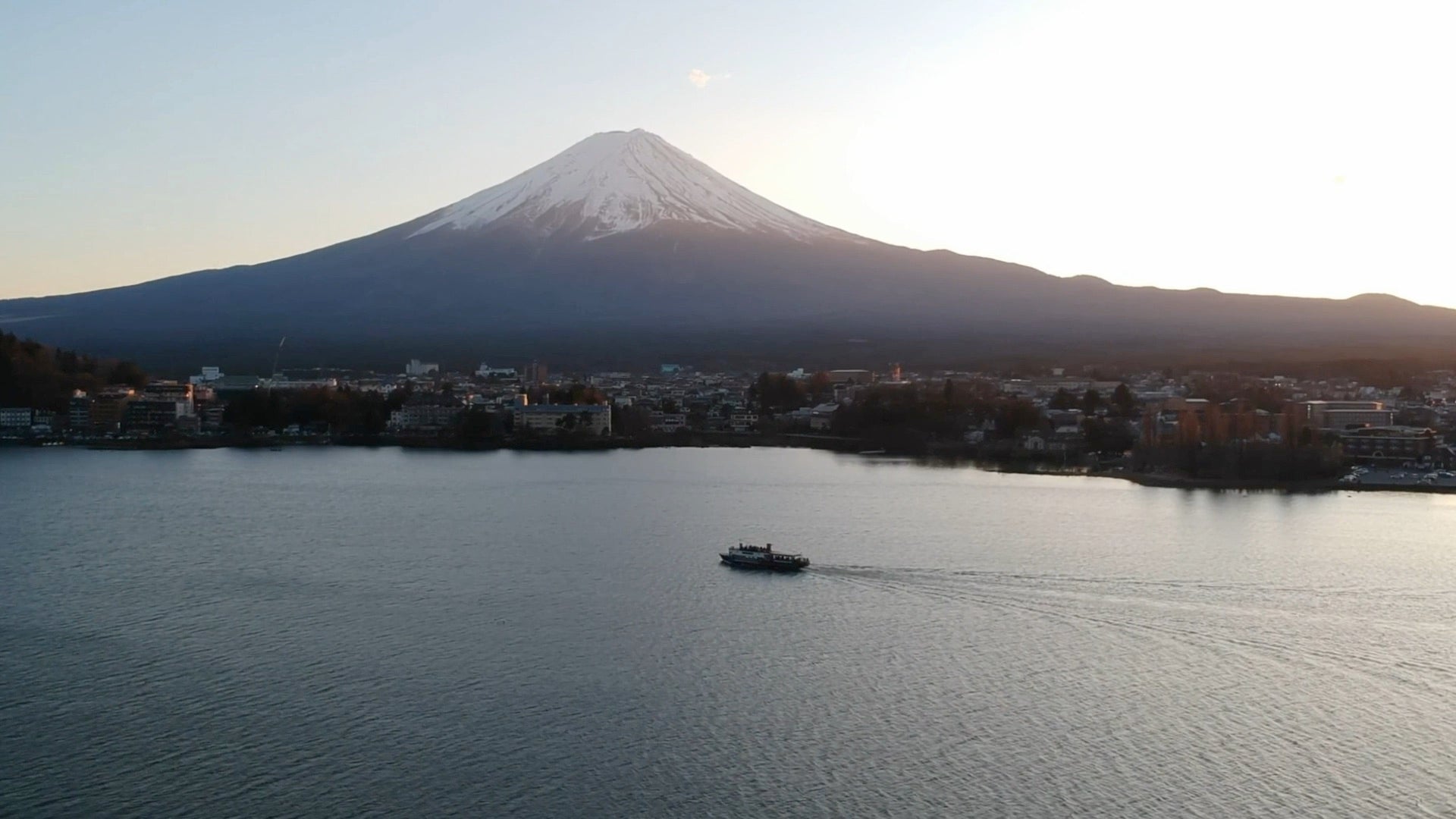 Mount Fuji above Lake Kawaguchi at dusk, a boat crossing the water