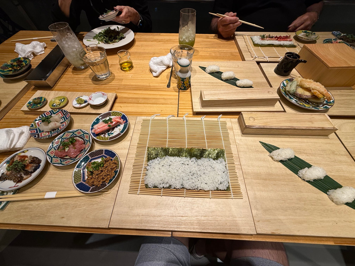 Guests preparing sushi together around a wooden counter